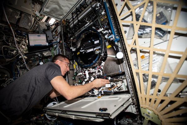 NASA astronaut Chris Cassidy works on the Combustion Integrated Rack, a device that enables safe fuel, flame and soot studies in microgravity.