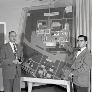 Two men with model of 10x10 wind tunnel