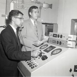Two men at control panel.