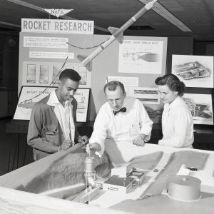 Three people examining model of the RETF.