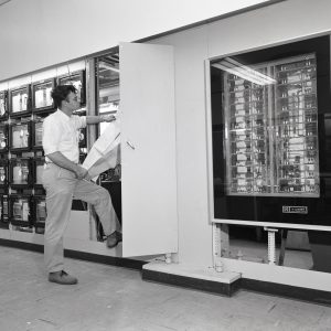 Man examines data recorders in control room.
