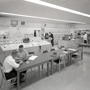 Men at various stations in control room