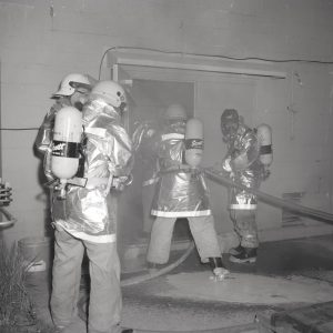 Firemen entering test cell.