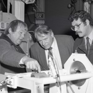 Three men examine hardware