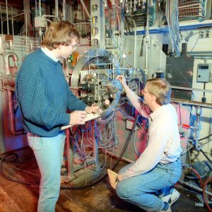Two men examine test setup.