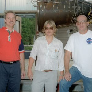 Three men in front of engine