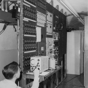 A technician installs equipment in the Pilot Plant control room