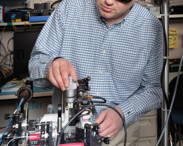 NASA researcher wearing laser safety goggles aligns optics