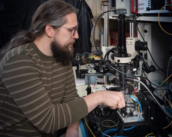 NASA scientist places photonic chips beneath a microscope objective