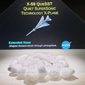 Projected on the surface of a pyramid-shaped glass display is the computer-generated image of a supersonic jet. Cotton balls place in the enclosure below it serve to represent clouds.