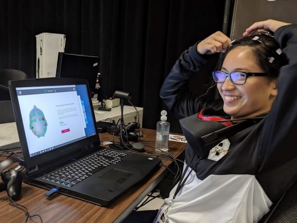 Kristina Martinez uses EEG and VR headsets in front of a computer.