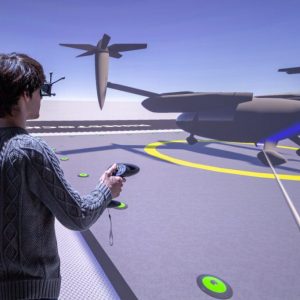 A man wearing 3D glasses with trackers and holding a joysticks interacts with a large display. On the display is the computer generated imagery of a VTOL “air taxi” sitting on a landing pad.
