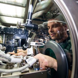 NASA astronaut Reid Wiseman installs Capillary Channel Flow (CCF) experiment hardware in the Microgravity Science Glovebox (MSG). (NASA)